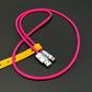 Hot pink braided fast charging cable secured with a yellow leather strap.