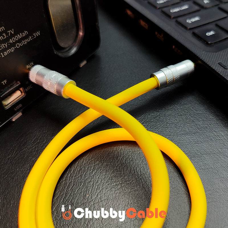 Yellow aux cord plugged into a portable speaker audio input port