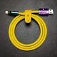 Yellow silicone USB to Lightning charging cable featuring rainbow metal ends and yellow leather tie.