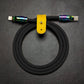 Black silicone USB-C to Lightning charging cable with rainbow metal connectors and yellow leather strap.