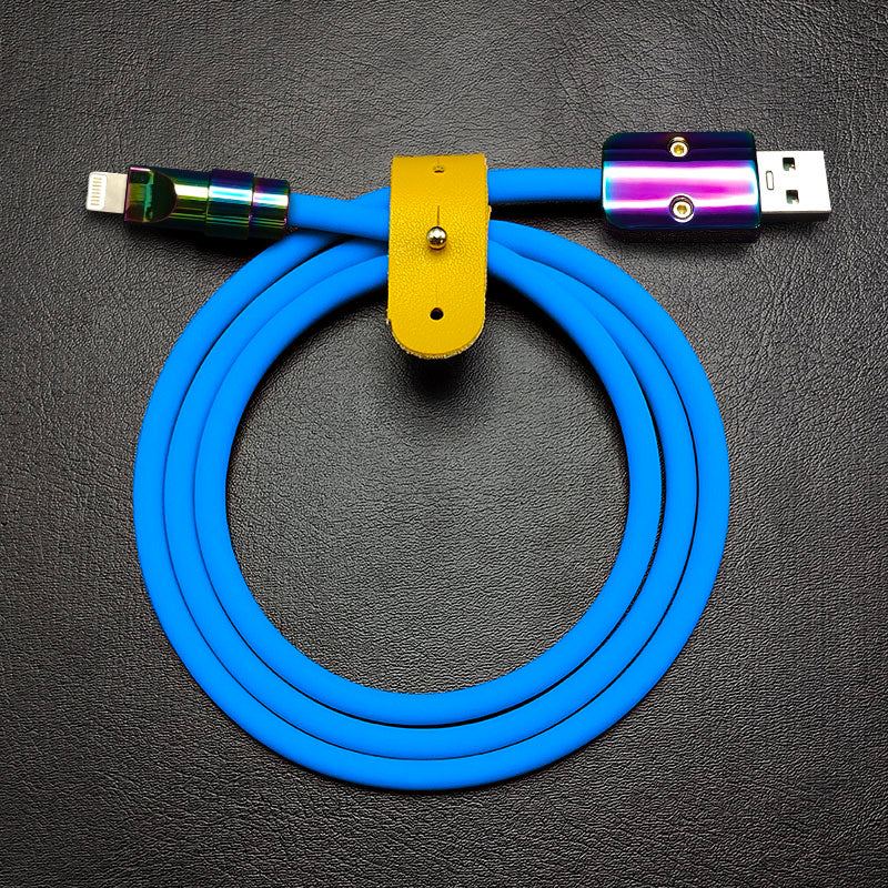 Blue silicone USB to Lightning cable with rainbow metal connectors and yellow leather strap.