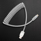 Grey coiled USB to Lightning cable on carbon fiber background