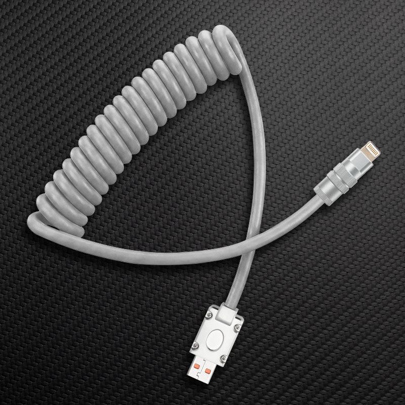 Grey coiled USB to Lightning cable on carbon fiber background