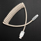 Beige coiled USB to Type-C cable on carbon fiber background