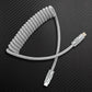 Grey coiled USB-C to Lightning cable on carbon fiber texture.