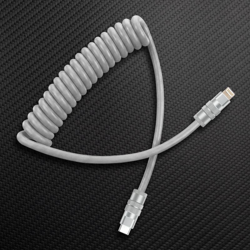 Grey coiled USB-C to Lightning cable on carbon fiber texture.