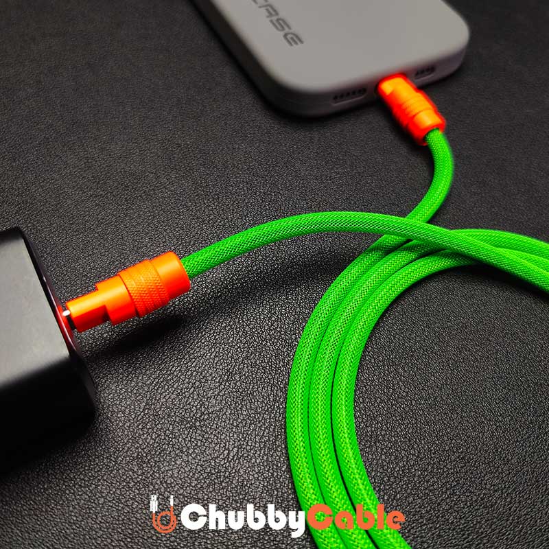 Green braided Chubby Cable with orange connectors charging a phone from a power adapter