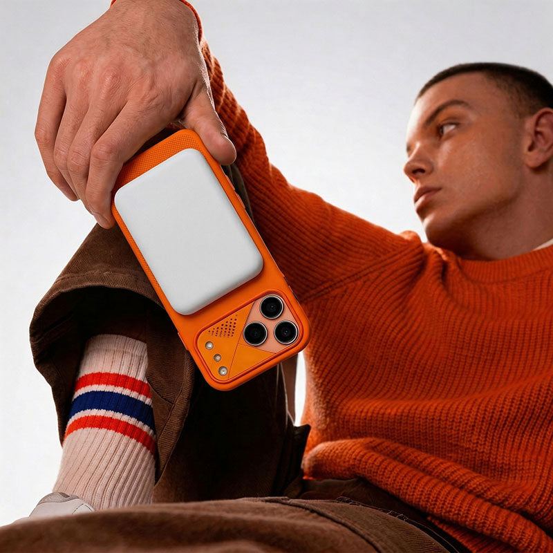 Person holding an orange smartphone case with a magnetic wireless charger attached.