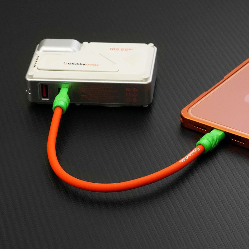 Short orange USB Type C silicone cable charging a smartphone from a power bank.