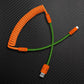 Orange and green coiled USB-A to Type-C braided cable against a carbon fiber background.