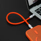 Orange short ChubbyCable charging smartphone from laptop