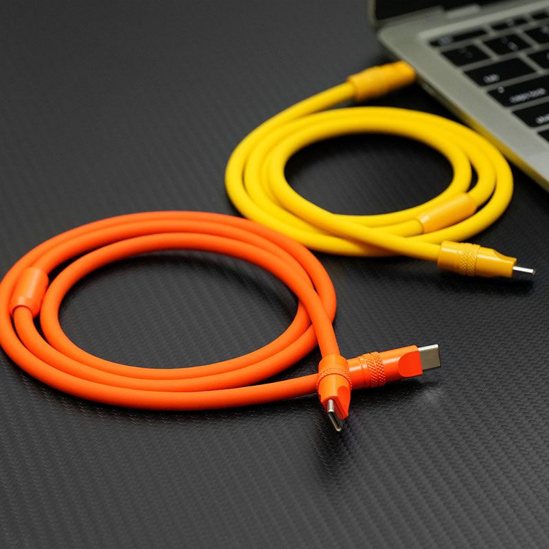 Orange and yellow thick silicone Type-C cables coiled next to a laptop.