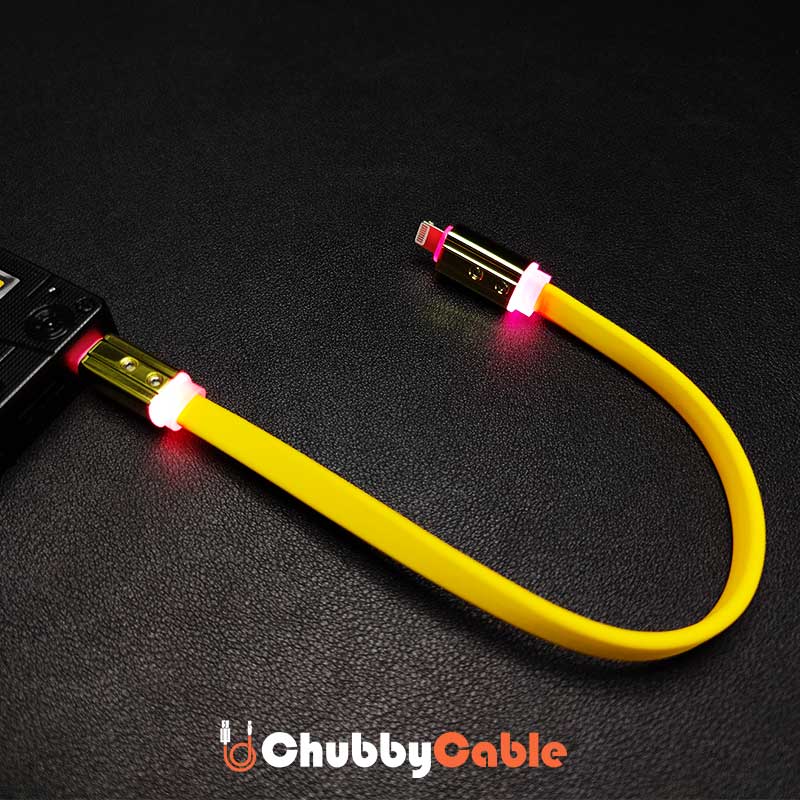 Yellow flexible short USB-C to Lightning cable glowing red connected to power bank
