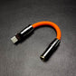 Orange USB C to 3.5mm female audio jack adapter with gunmetal accents.
