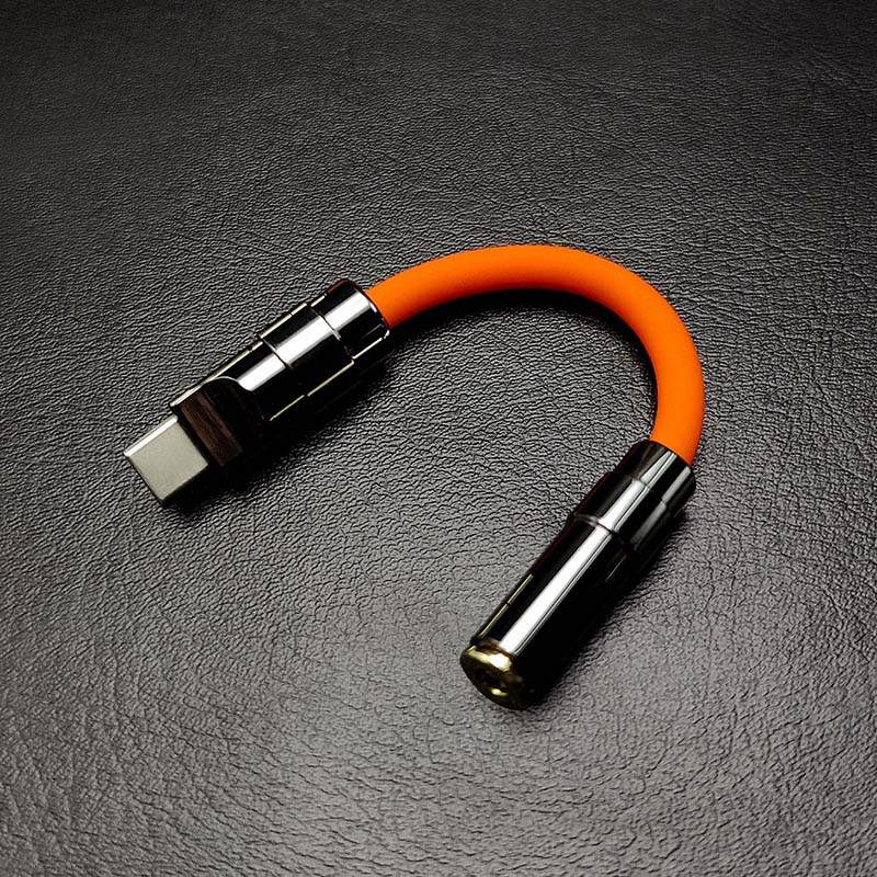 Orange USB C to 3.5mm female audio jack adapter with gunmetal accents.