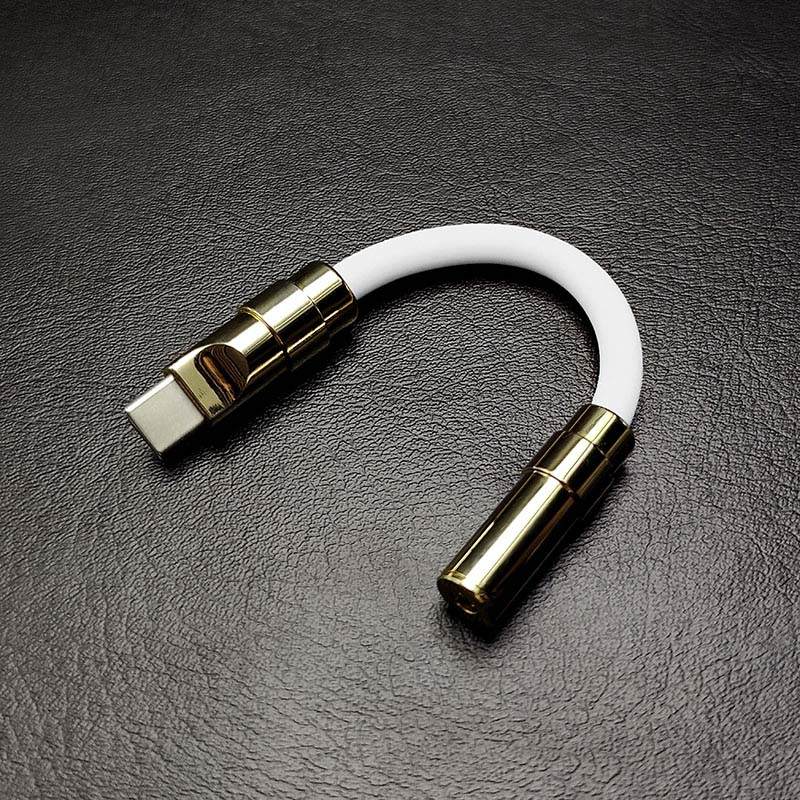 White USB-C to 3.5mm audio jack adapter with gold metallic hardware.