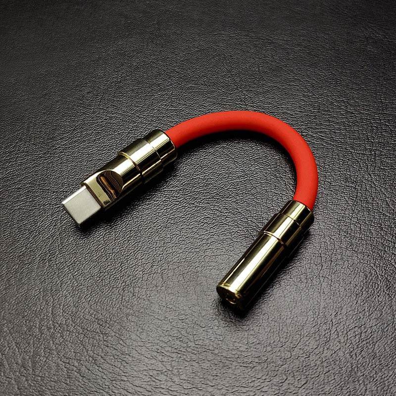 Red silicone USB C to headphone jack adapter with gold metallic ends.