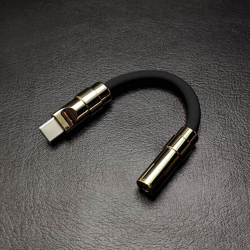 Matte black USB-C to 3.5mm audio jack adapter with gold metallic hardware.