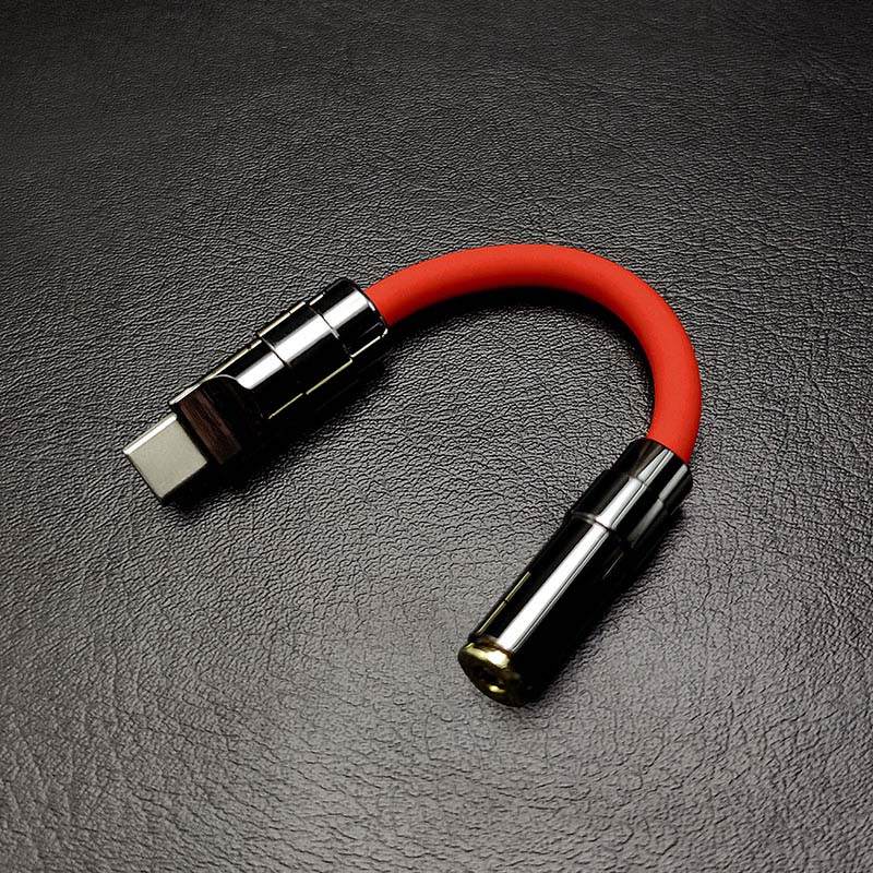 Red USB-C to 3.5mm audio jack dongle with dark chrome connectors.