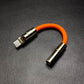 Thick orange USB-C to 3.5mm headphone adapter with gold metal housing.