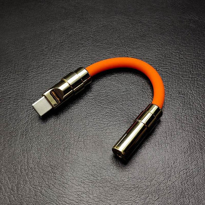 Thick orange USB-C to 3.5mm headphone adapter with gold metal housing.